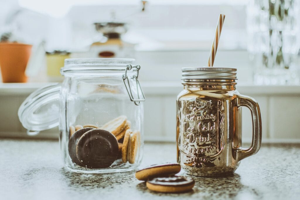 Freelance money and personal finance. Glass of milkshake with cookies in a jar on a sunny kitchen countertop.