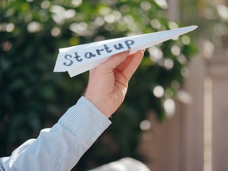 Close-up of a hand holding a paper plane with 'Startup' written, symbolizig starting budgeting