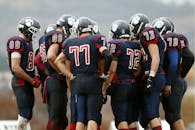 American football players in a huddle planning their next move on a grassy field.