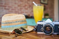 A stylish scene showcasing a vintage camera, hat, and orange juice, evoking summer travel vibes, a goal you can aspire to by budgeting.