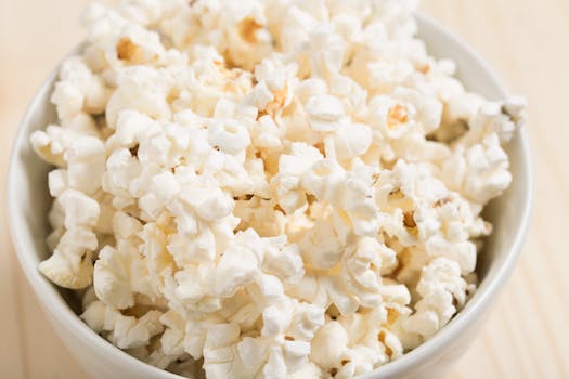 Enjoying life on a budget. Close-up of freshly popped popcorn in a white bowl, perfect for a movie night snack.
