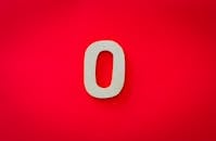 Close-up of a zero cutout on a bright red background with vibrant contrast.