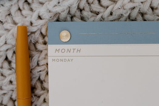 Close-up of a modern planner with a gold pen on a textured background.