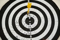 Close-up of a dart hitting the bullseye on a black and white target board symbolizing success.