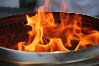 Close-up image of bright orange flames dancing inside a metal fire pit.